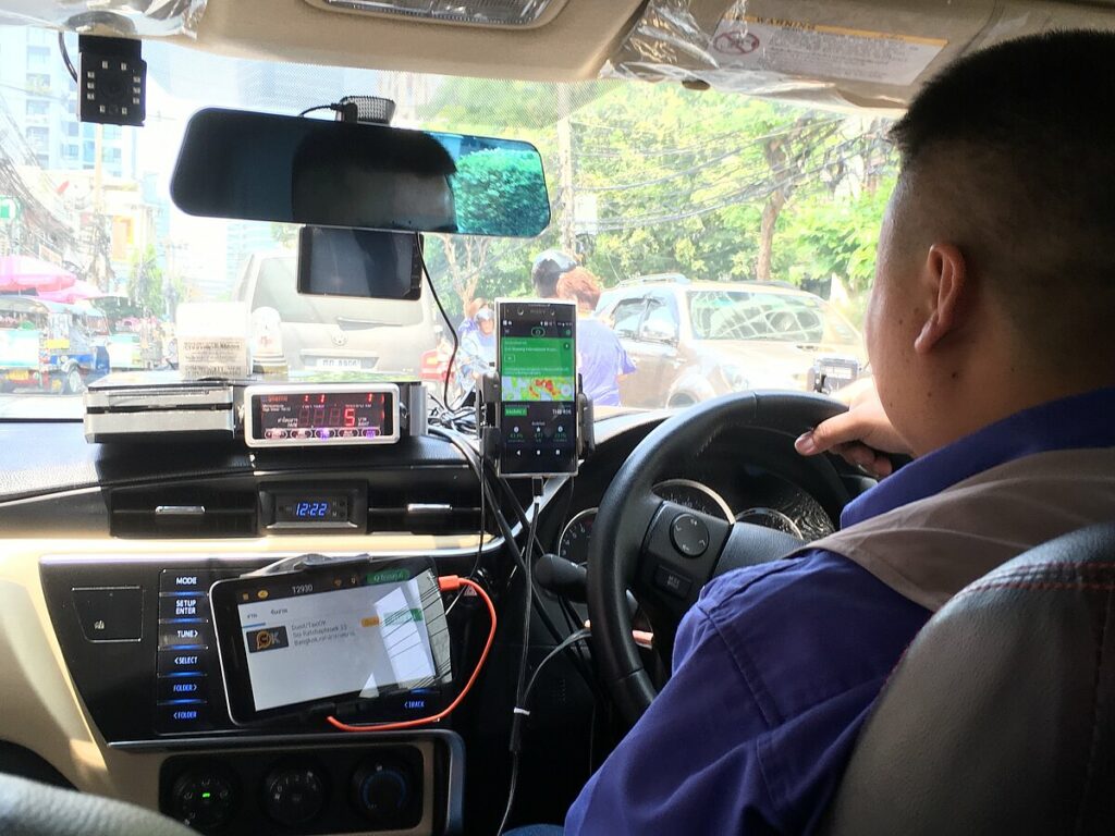 Taxi driver in Bangkok as he uses different apps, one at the time, to get a passenger. Photo: Akkanut Wantanasombut.